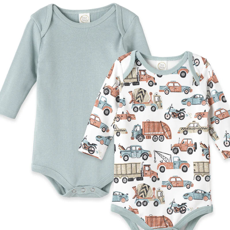 Two long-sleeve bodysuits: one dusty blue with cars-trucks print, one solid dusty aqua. Snap closures, envelope neck.