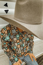 Load image into Gallery viewer, A boy wearing a cowboy hat is leaned into the camera with his face out of frame. His button-up shirt is checkered with different images such as cacti, saddles, cowboy boots, and lasso rope. He  is sitting on a trailer.