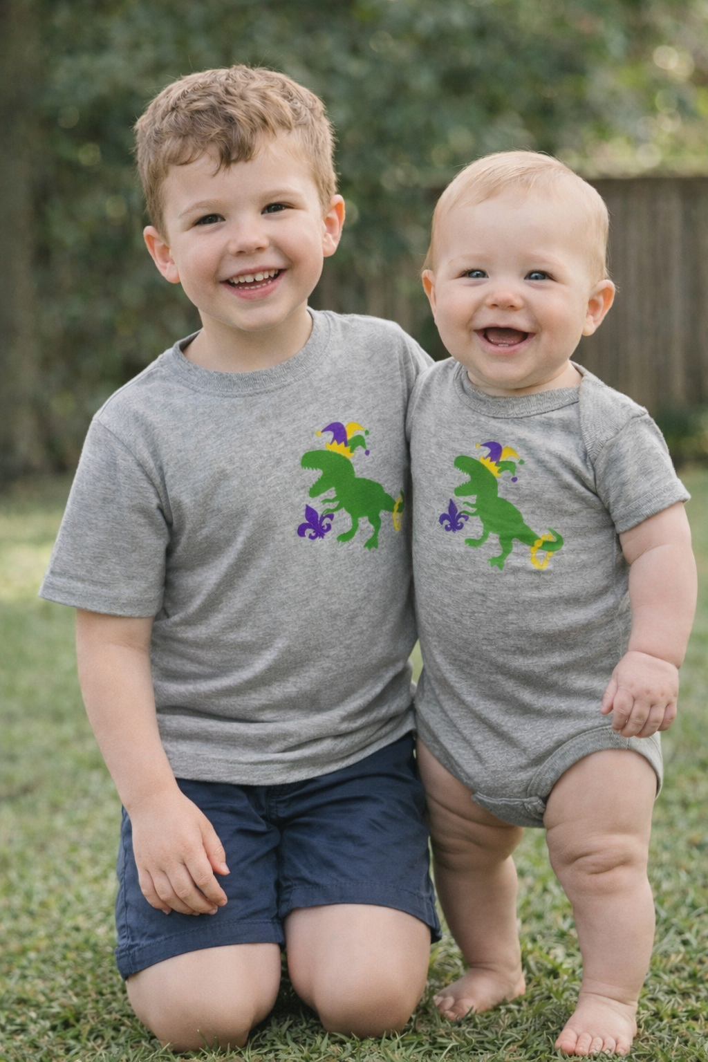 Heather gray short-sleeve tee with purple, green, and yellow Mardi Gras dinosaur graphic by Sweet Wink