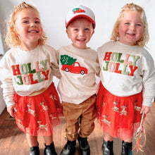 Load image into Gallery viewer, Three young children wearing festive holiday outfits, including 'Holly Jolly' embroidered sweaters for the girls with red skirts featuring gold reindeer, and a boy in a cream sweater with a red truck and Christmas tree design, paired with brown pants and a matching red truck baseball cap. Perfect for Christmas family outfits.