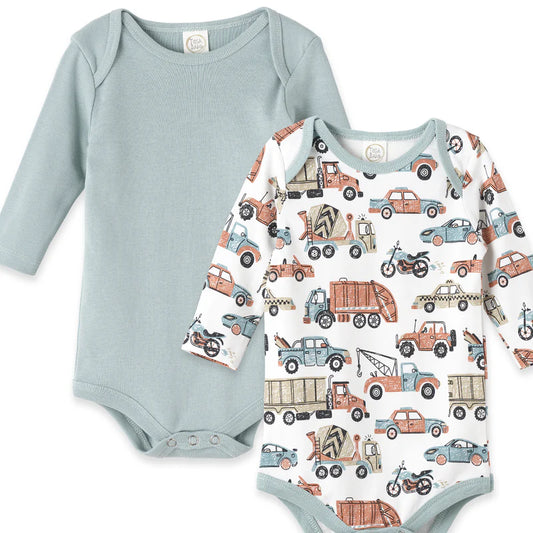 Two long-sleeve bodysuits: one dusty blue with cars-trucks print, one solid dusty aqua. Snap closures, envelope neck.