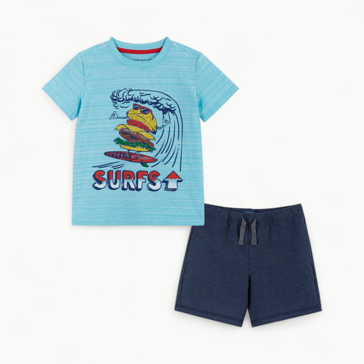 A Light blue crewneck t-shirt featuring a burger character wearing red sunglasses. The burger is riding some tidal waves on a red surfboard. The shirt is paired with a navy blue pair of cotton drawstring shorts. 