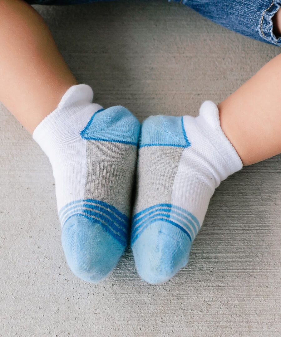 A toddlers feet in a pair of blue and white ankle socks.