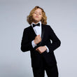 Child wearing a black tuxedo with a white shirt and bow tie on a gray background