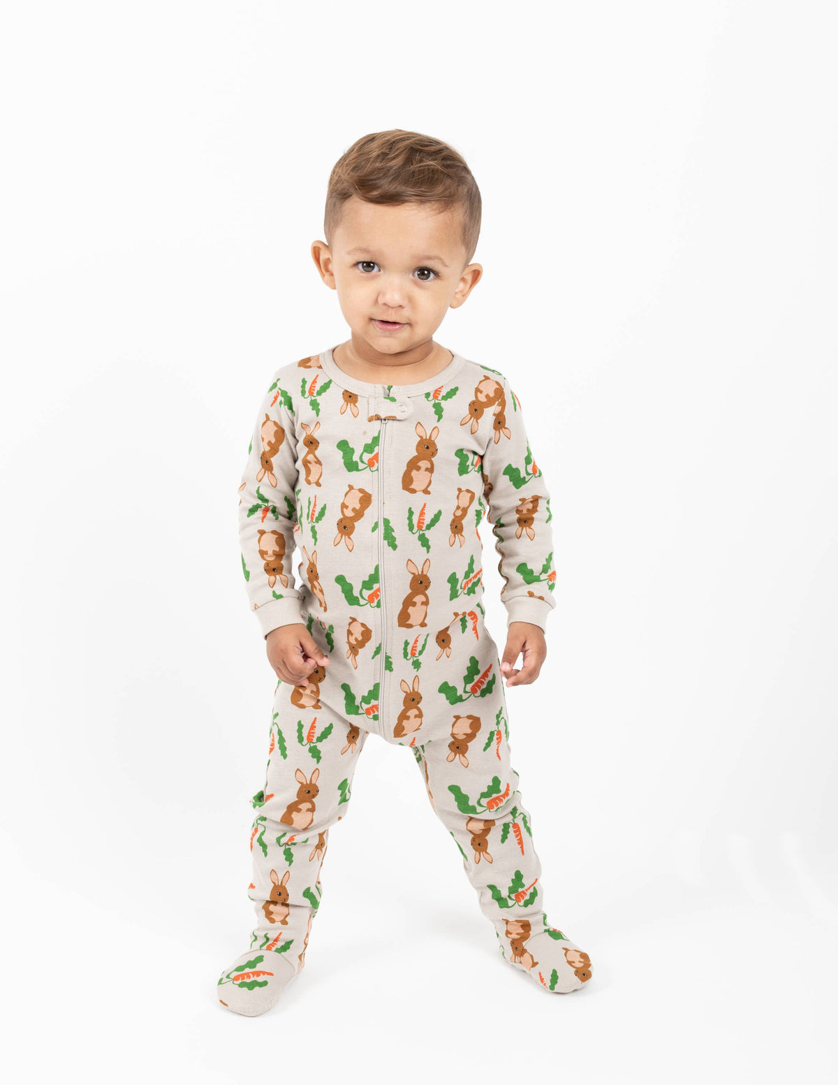 Happy baby wearing Easter bunny-themed footie pajama romper for toddlers with carrots and green leaves print — soft cotton baby sleepwear outfit