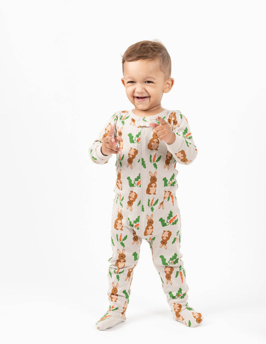 Happy baby wearing Easter bunny-themed footie pajama romper for toddlers with carrots and green leaves print — soft cotton baby sleepwear outfit