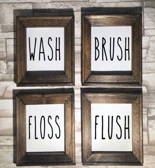 Set of four framed canvas artworks with dark walnut frames displaying Wash, Brush, Floss, and Flush