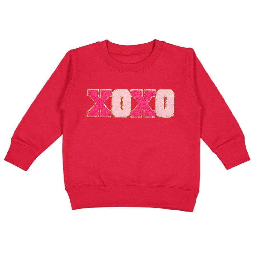 Red crewneck sweatshirt with light and hot pink chenille XOXO patch outlined in gold glitter