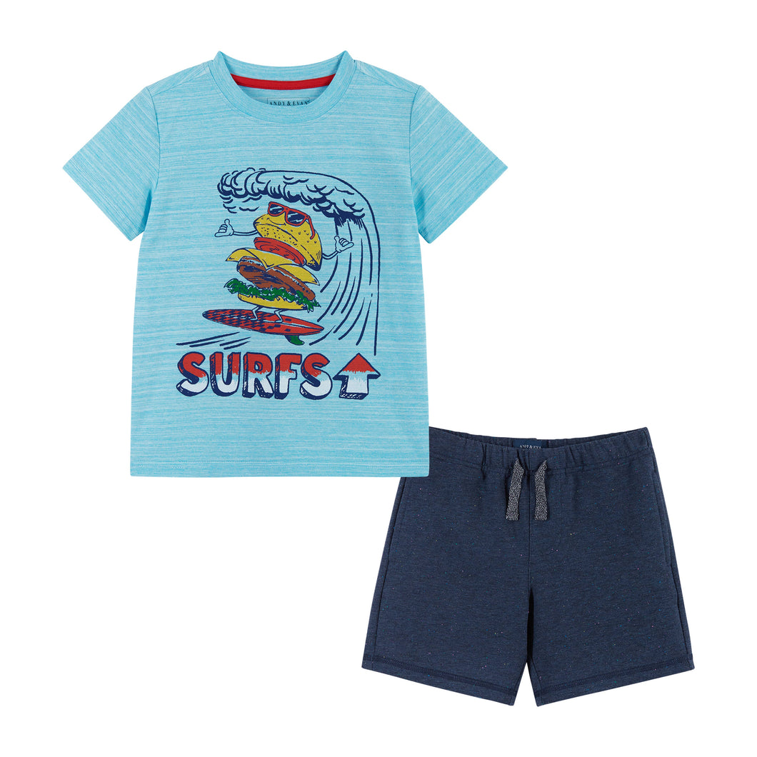 A Light blue crewneck t-shirt featuring a burger character wearing red sunglasses. The burger is riding some tidal waves on a red surfboard. The shirt is paired with a navy blue pair of cotton drawstring shorts. 