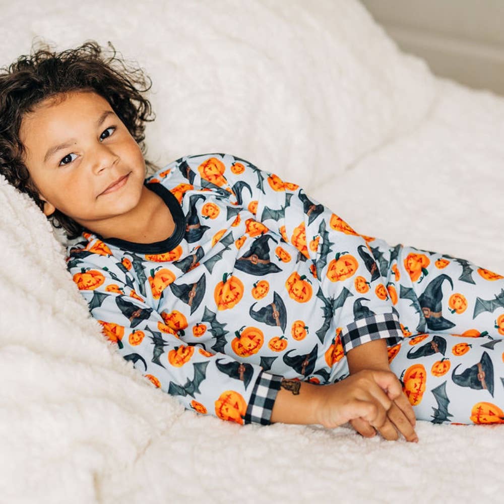 White buttflap pajamas with orange pumpkins, black hats and bats, and black plaid cuffs by Sugar Bee Clothing