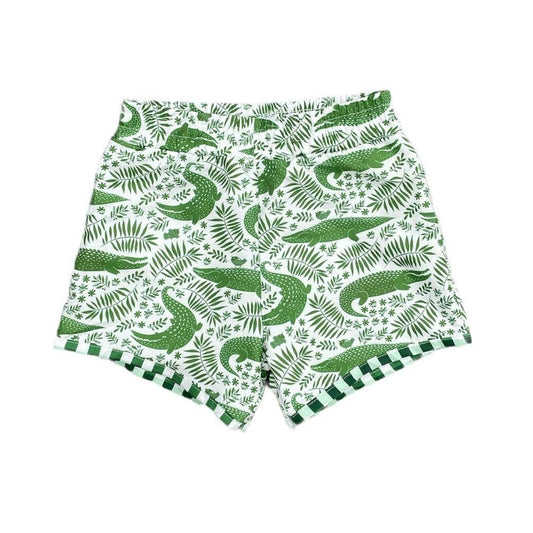 White swim trunks with green alligator and plant leaf details.  The bottom hem is striped with the same white and green colors. 